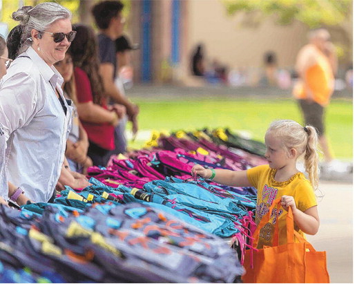 Four-year-old Elizabeth Larose selects a backpack filled with school supplies as New Mexico State Representative Kathleen Cates watches on Sunday at the Cruzin’ into the School Year event at Civic Plaza in Downtown Albuquerque. The event provided free backpacks, haircuts and other essentials to students and their families. MIKE SANDOVAL/FOR THE JOURNAL